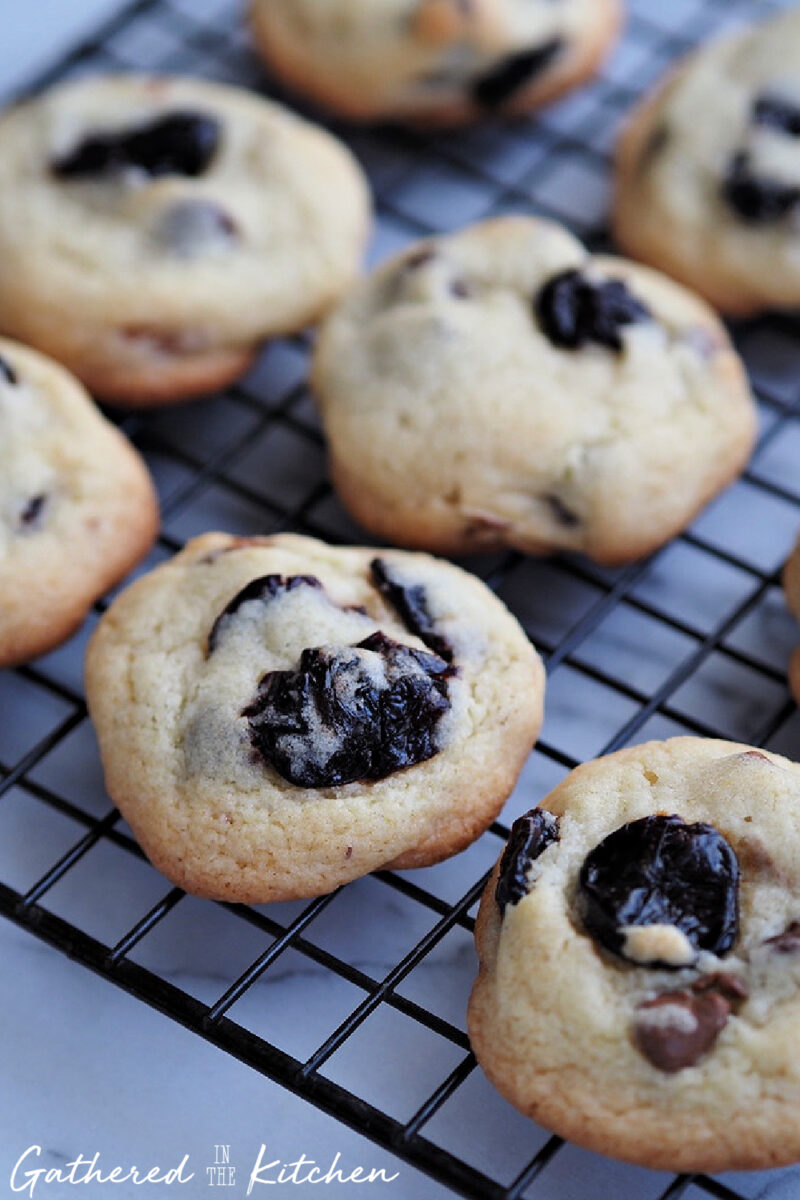 Bakery style cherry almond chocolate chip cookies cooling on a baking rack. | Gathered In The Kitchen 