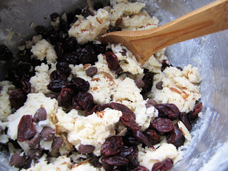 Mixing dried cherries, slivered almonds, and chocolate chips into cookie dough. | Gathered In The Kitchen 