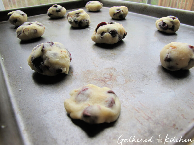 Cherry almond chocolate chip cookie dough balls spaced on baking sheet before baking. | Gathered In The Kitchen 