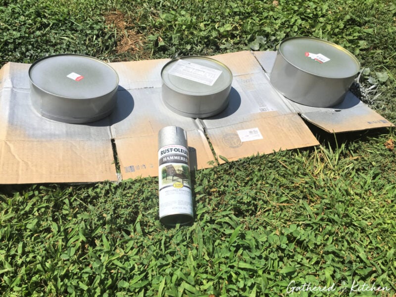 Three cookie tins spray painted silver outdoors on cardboard with spray paint can | Gathered In The Kitchen 
