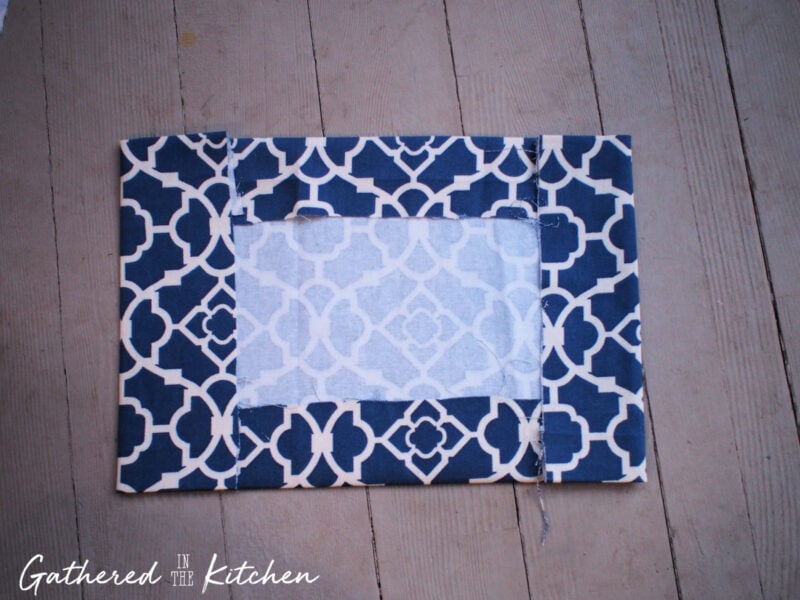 Blue patterned cotton fabric folded with clean hems, showing pockets formed on each side to create a DIY no-sew slip-on fabric book cover.