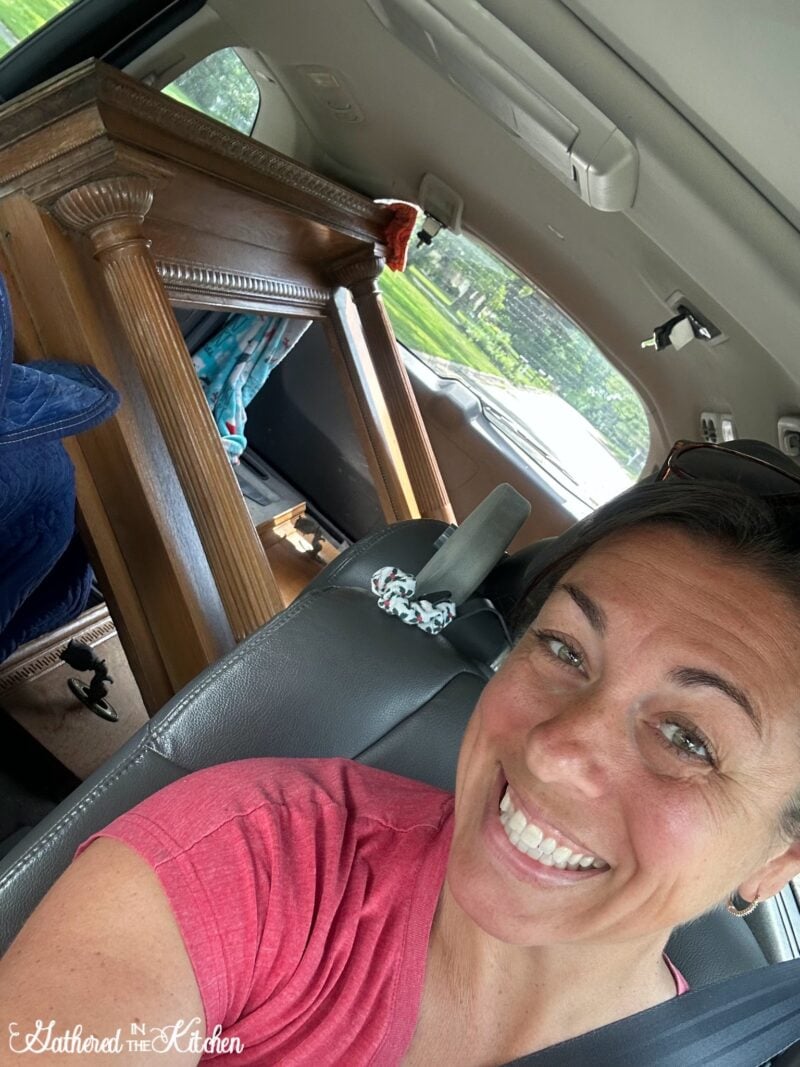 Smiling woman in a car with a vintage oak fireplace mantel loaded in the backseat, excited to bring it home for restoration in her 1886 Victorian house. | Gathered In The Kitchen 