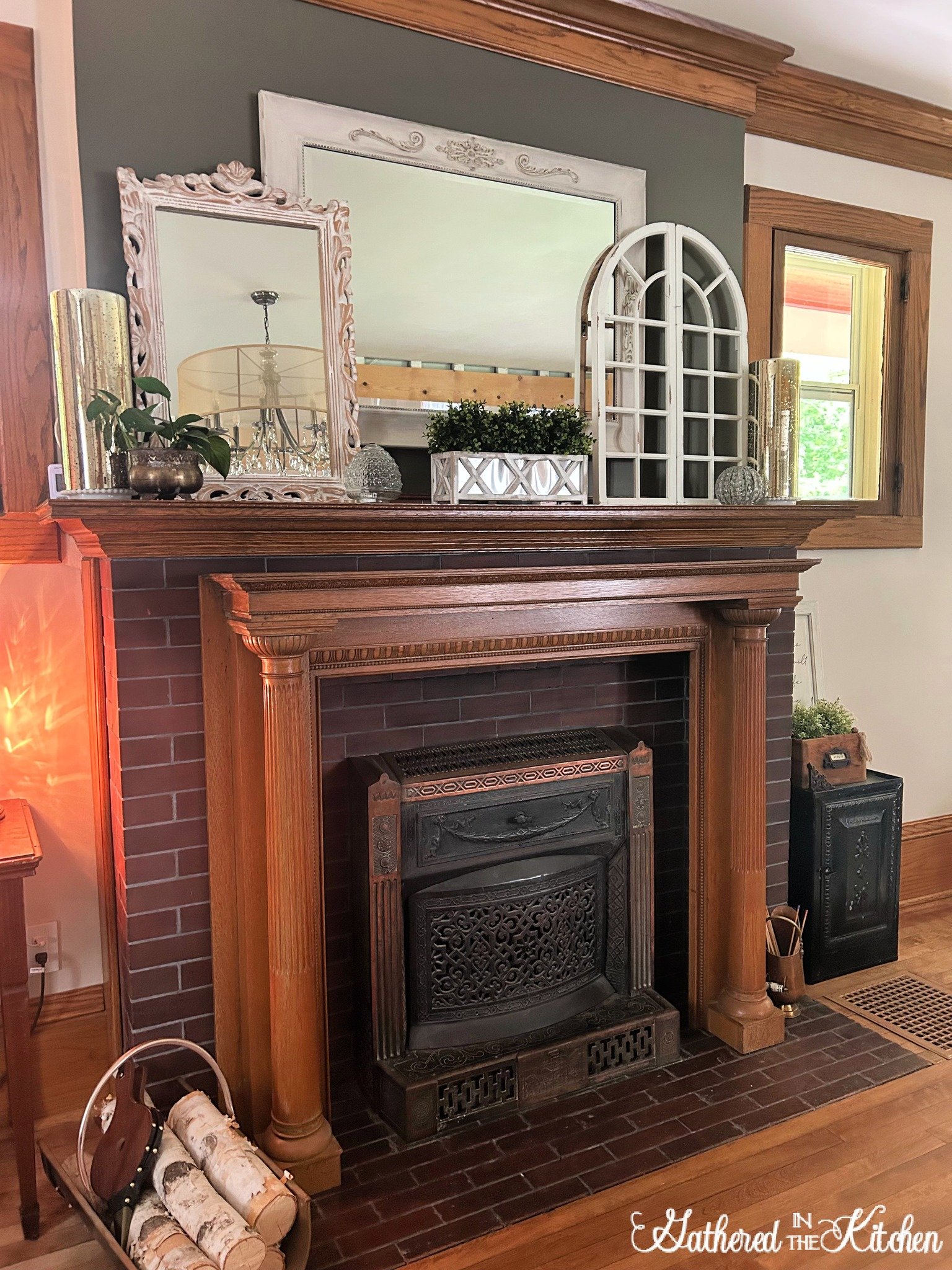 Restored 1906 Aldine fireplace in an 1886 Victorian home with a vintage oak mantel, decorative mirrors, greenery, and rustic accents styled on the mantelpiece. | Gathered In The Kitchen