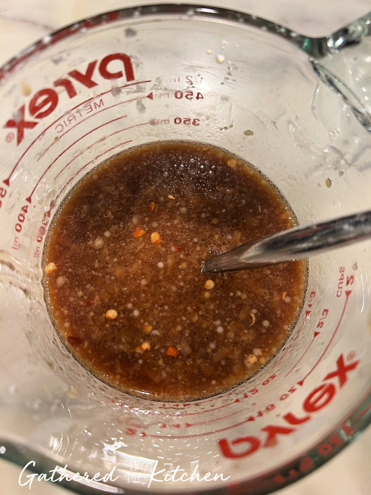 Homemade stir fry sauce mixed in a glass measuring cup with soy sauce, honey, garlic, ginger, red pepper flakes, and cornstarch before cooking | Gathered In The Kitchen