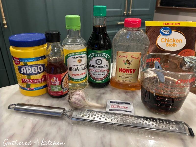 Ingredients for homemade stir fry sauce including soy sauce, chicken broth, honey, rice vinegar, sesame oil, garlic, ginger, cornstarch, and red pepper flakes on a kitchen counter | Gathered In The Kitchen