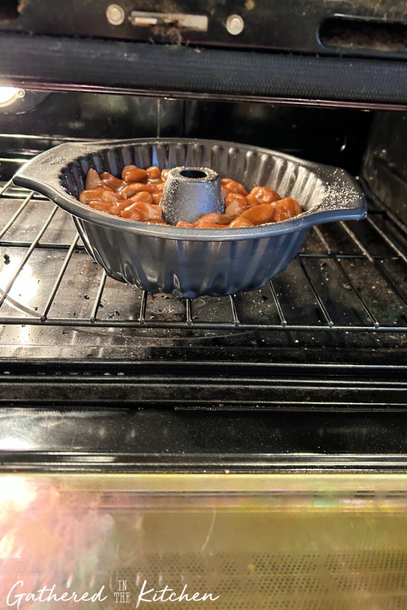 Bundt pan filled with monkey bread baking in oven. | Gathered In The Kitchen 