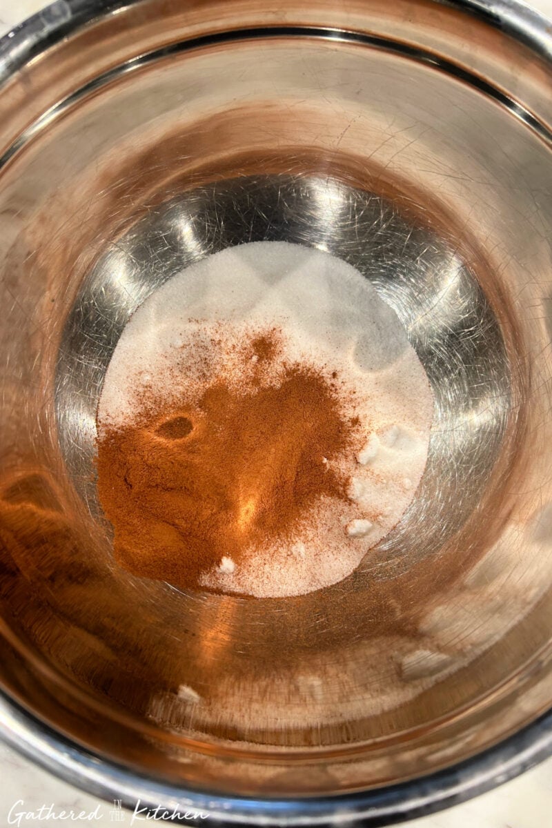 Bowl of cinnamon and sugar mixture for coating biscuit dough in monkey bread recipe. | Gathered In The Kitchen 