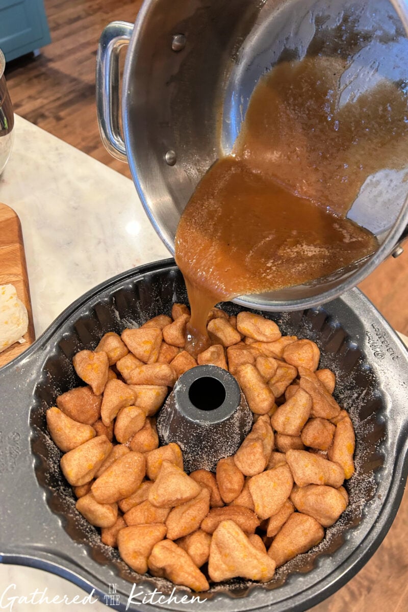 Brown sugar butter glaze poured over biscuit dough in Bundt pan for monkey bread. | Gathered In The Kitchen 