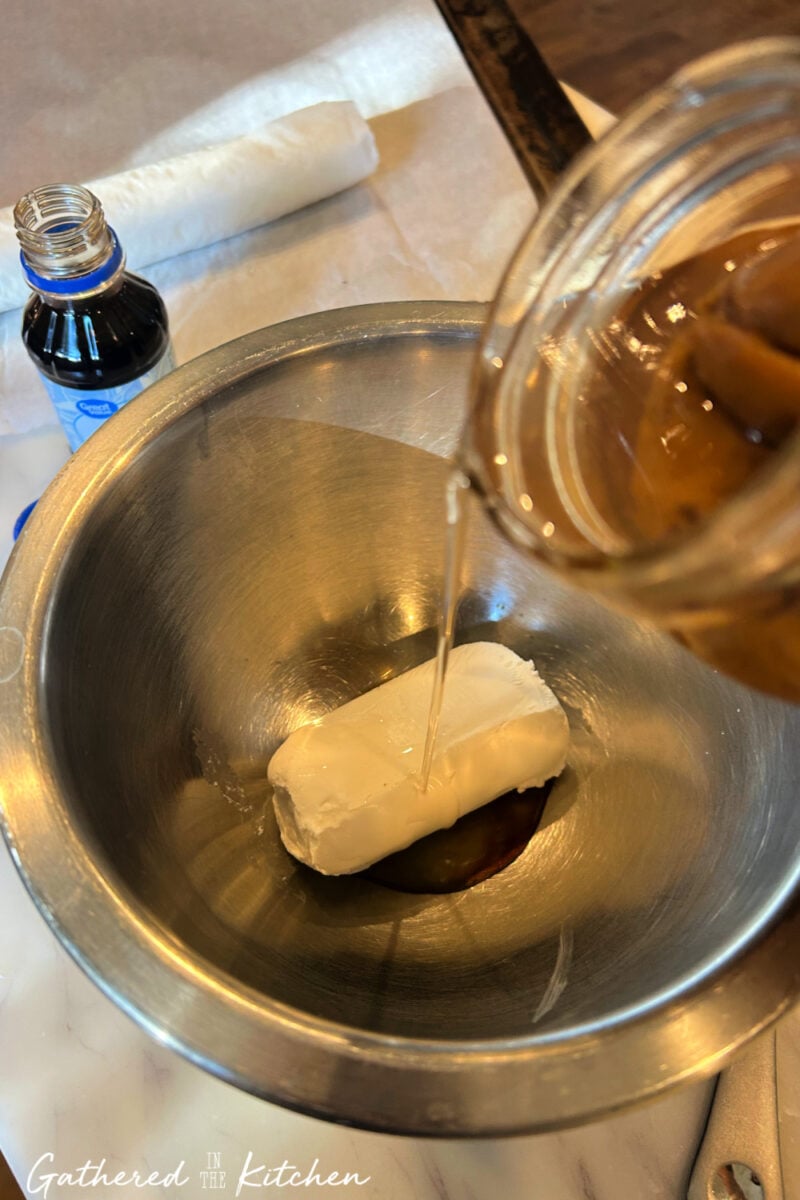 Goat cheese in a bowl with vanilla extract and peach juice being poured in to make danish filling | Gathered In The Kitchen 