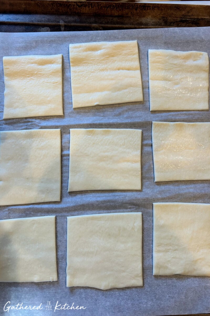 Puff pastry sheet cut into 9 squares on parchment paper for making homemade danishes | Gathered In The Kitchen 