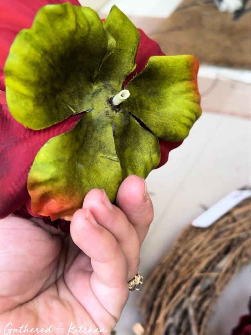 Close-up of the back of a red artificial flower showing how the flower head was removed from the stem for a DIY patriotic wreath made with thrift store faux flowers. | Gathered In The Kitchen 