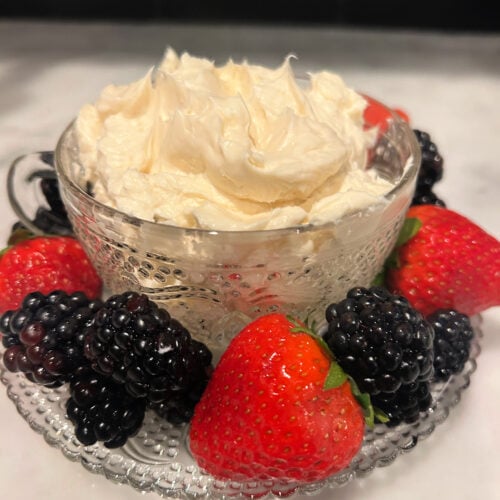 Fluffy cream cheese fruit dip served in a glass bowl surrounded by fresh strawberries and blackberries.