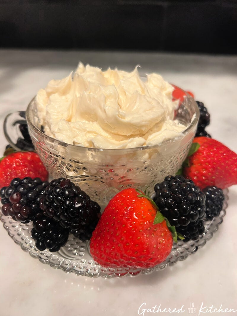 Fluffy cream cheese fruit dip served in a glass bowl surrounded by fresh strawberries and blackberries.